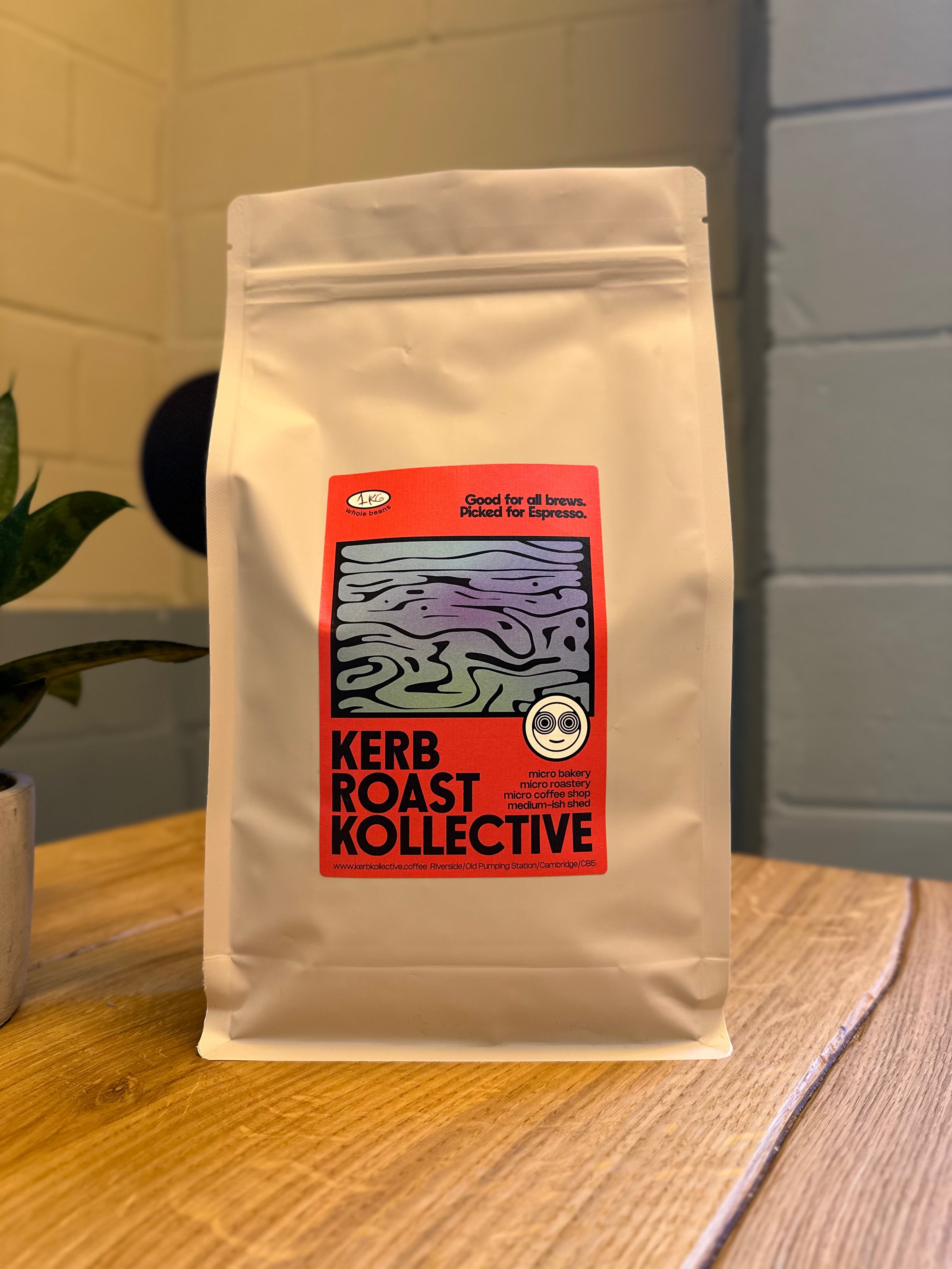 Kerb Kollective 1kg coffee bag on a wooden surface with a plant in the background